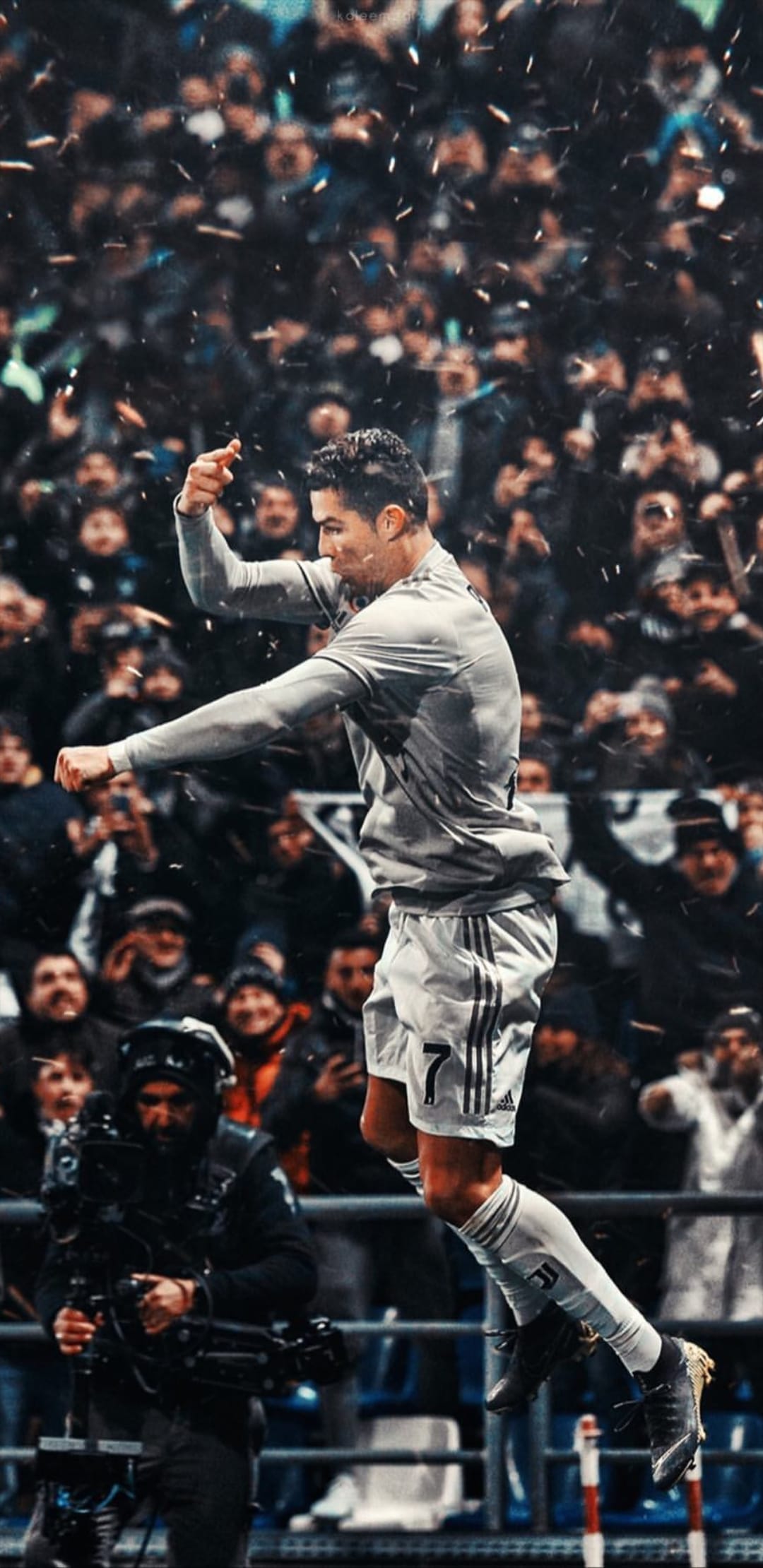 Cristiano Ronaldo leaps in mid-air with arms wide amidst falling confetti and a cheering crowd in a stadium.
