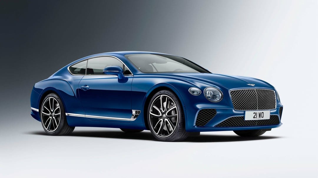 Blue Bentley Continental GT luxury car parked in a studio with soft lighting and a minimalist gray gradient background.