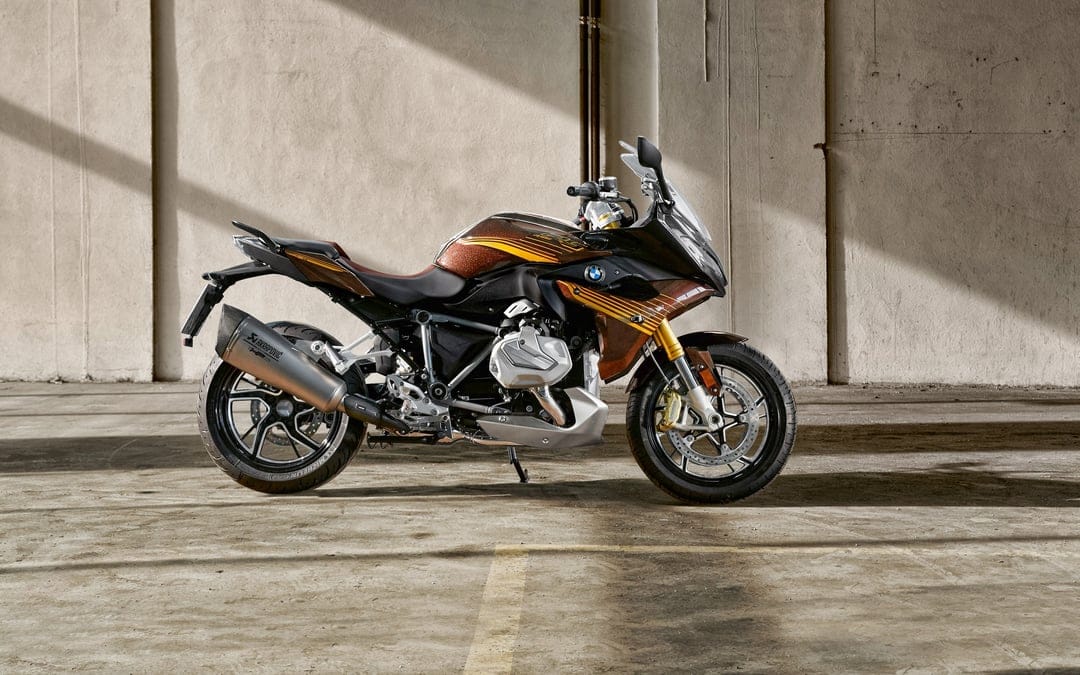 A custom brown and gold BMW R 1250 RS motorcycle parked against a concrete wall with sharp sunlight shadows.