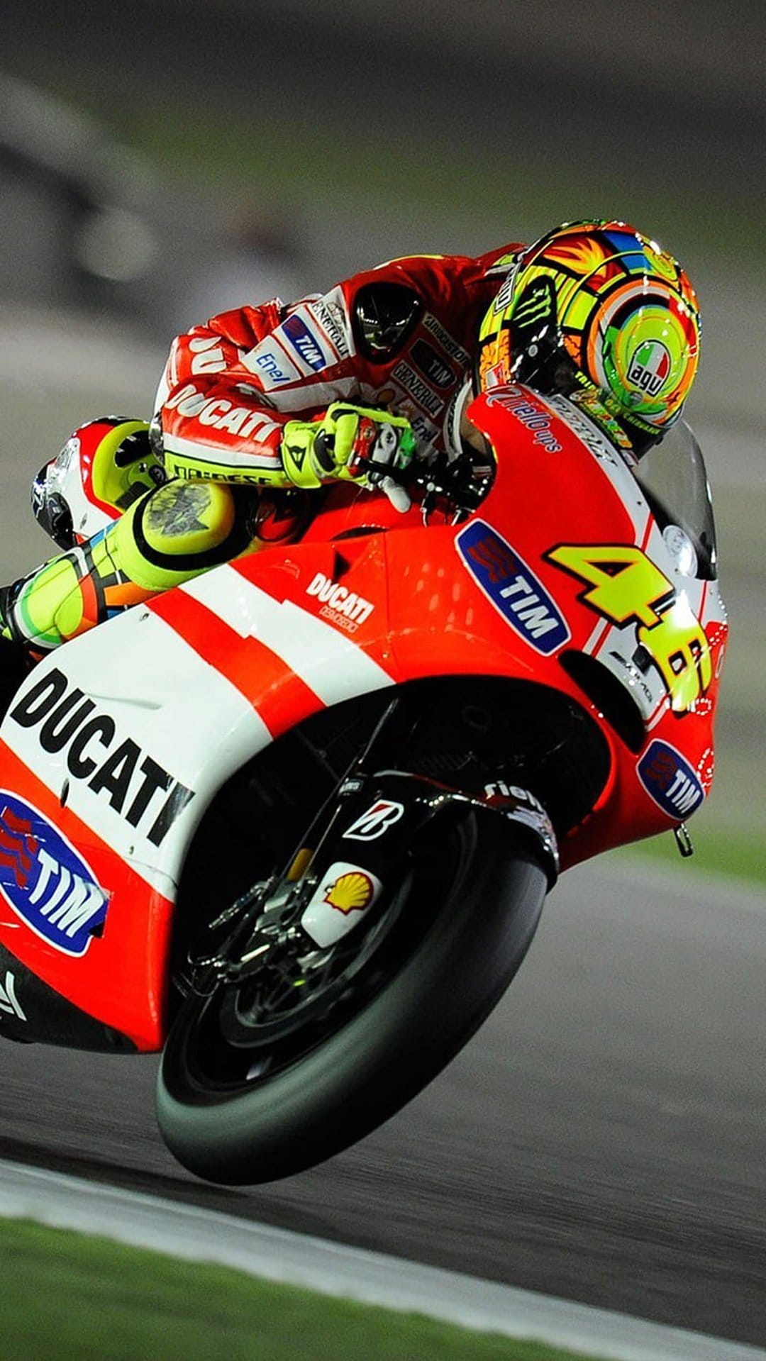 Valentino Rossi on a red Ducati MotoGP bike with number 46 leaning deep into a racetrack corner during a race.