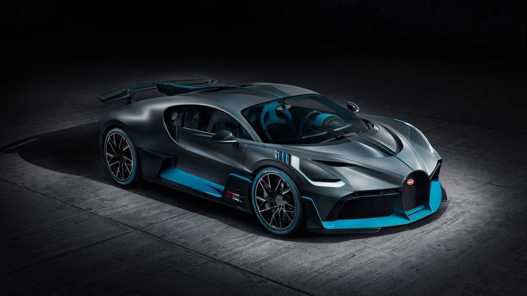 Bugatti Divo supercar in matte gray with cyan highlights parked on a textured concrete floor in a dark studio.