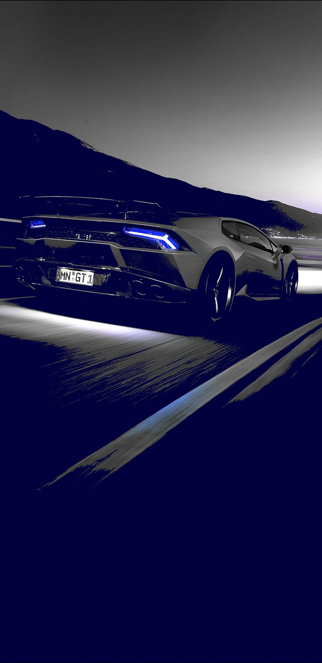 Lamborghini sports car speeds down a dark winding road with glowing blue taillights against twilight mountains.