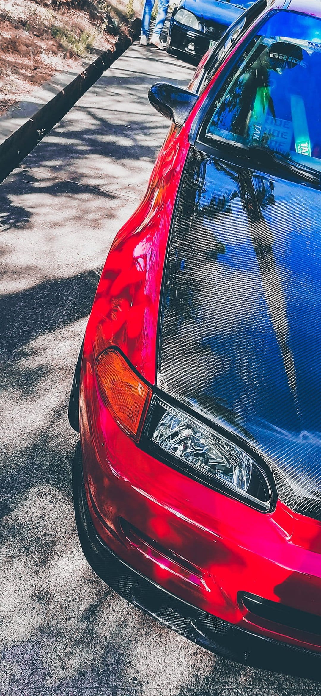 Red Honda Civic featuring a carbon fiber hood, clear headlights, and amber signals on a blurred street.