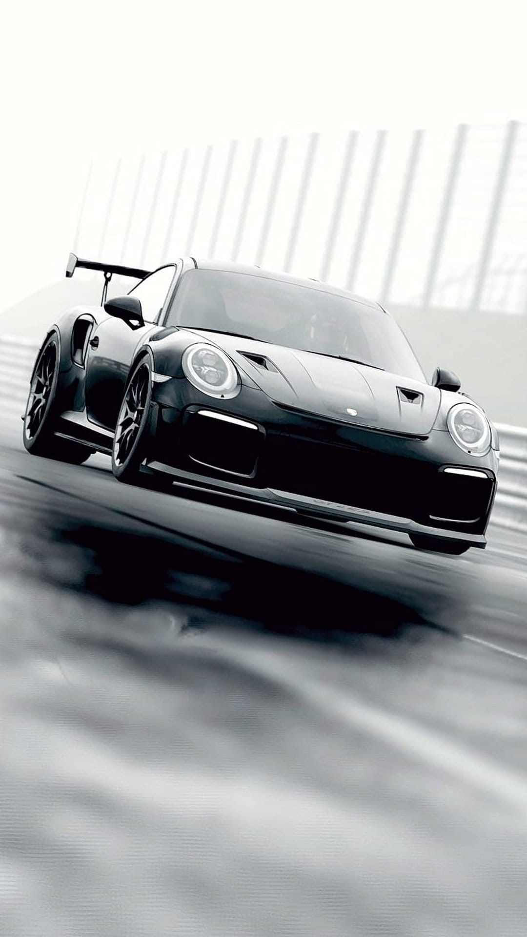 Porsche 911 GT2 RS racing on a wet asphalt track with water splashing behind the large rear wing in monochrome.