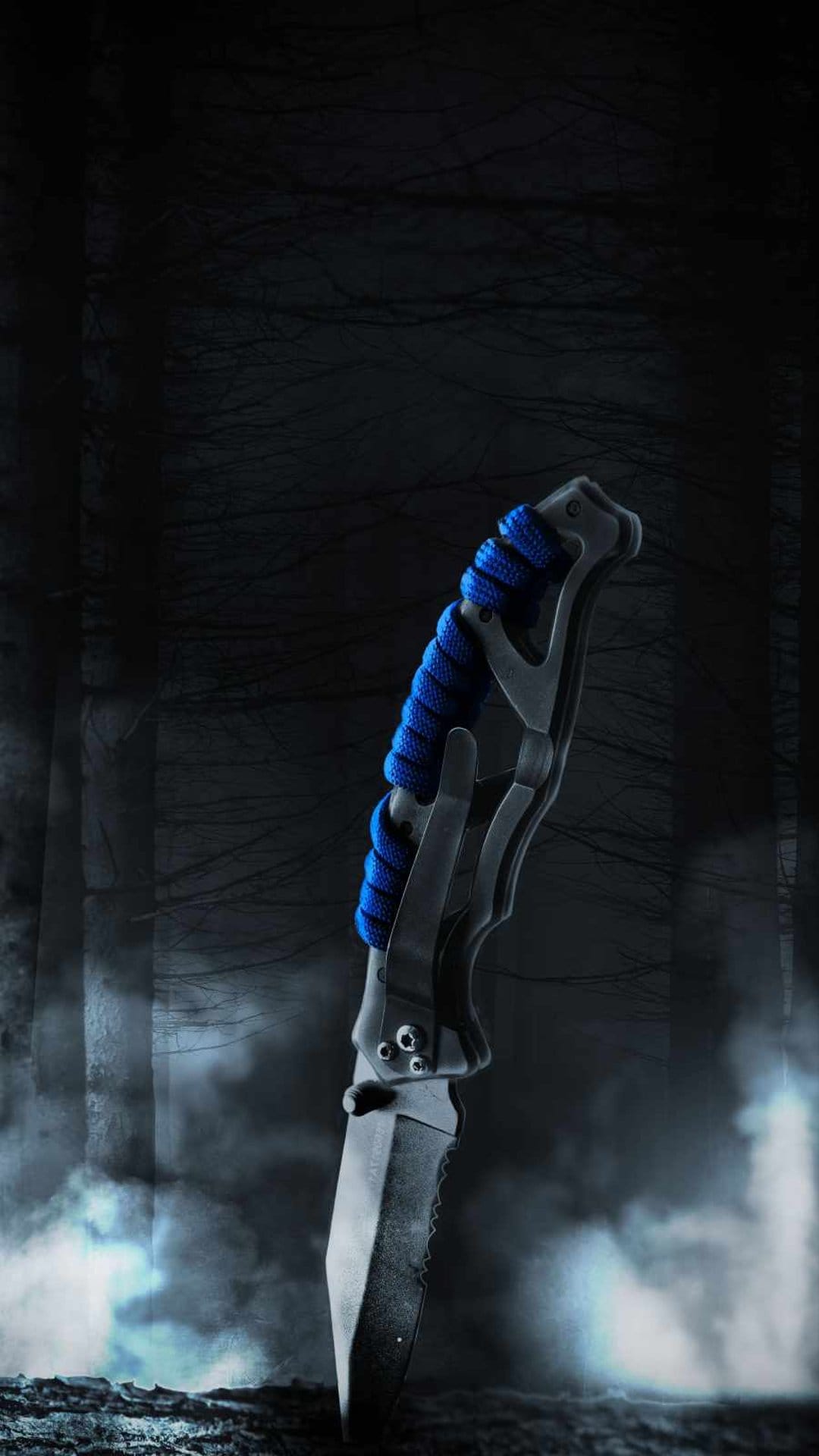 Tactical knife with blue paracord handle stuck in dark soil within a misty, atmospheric pine forest.