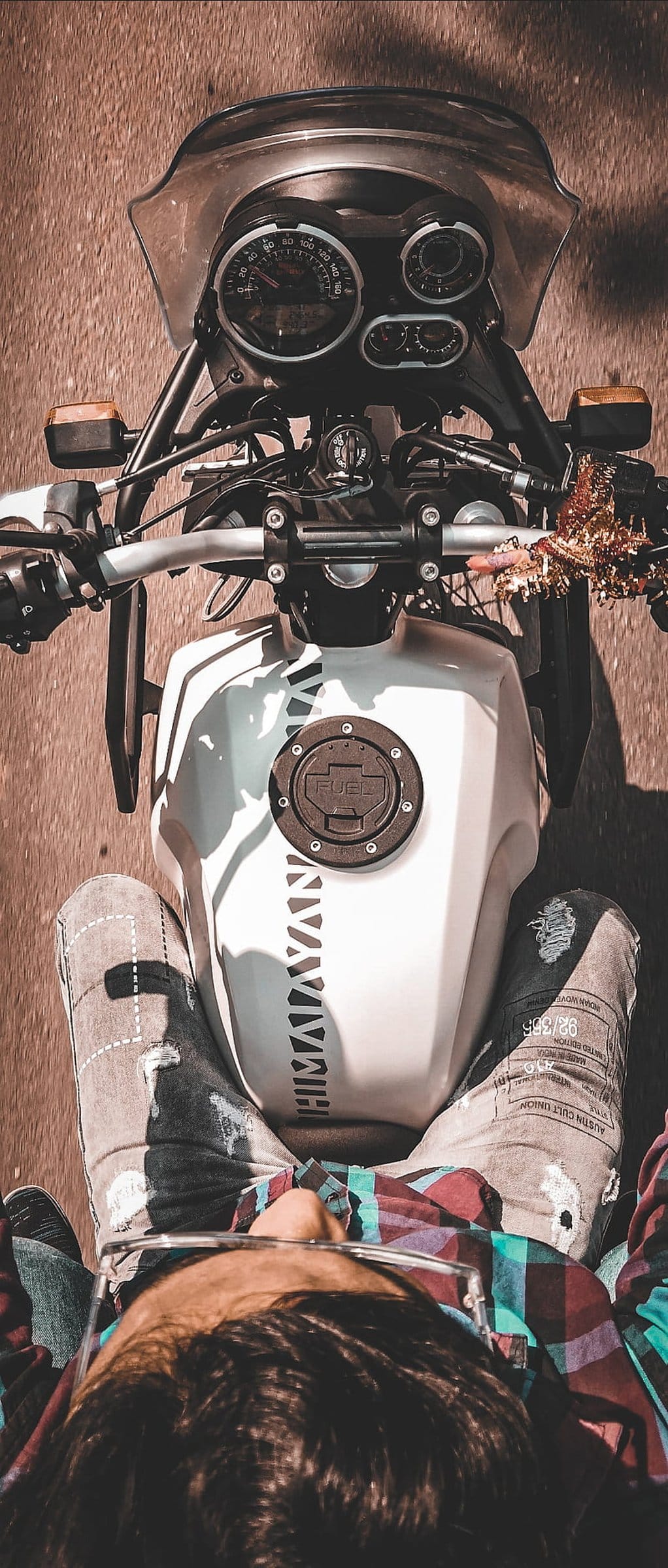 Royal Enfield Himalayan motorcycle rider wearing denim and plaid viewed from a first-person perspective on a road.