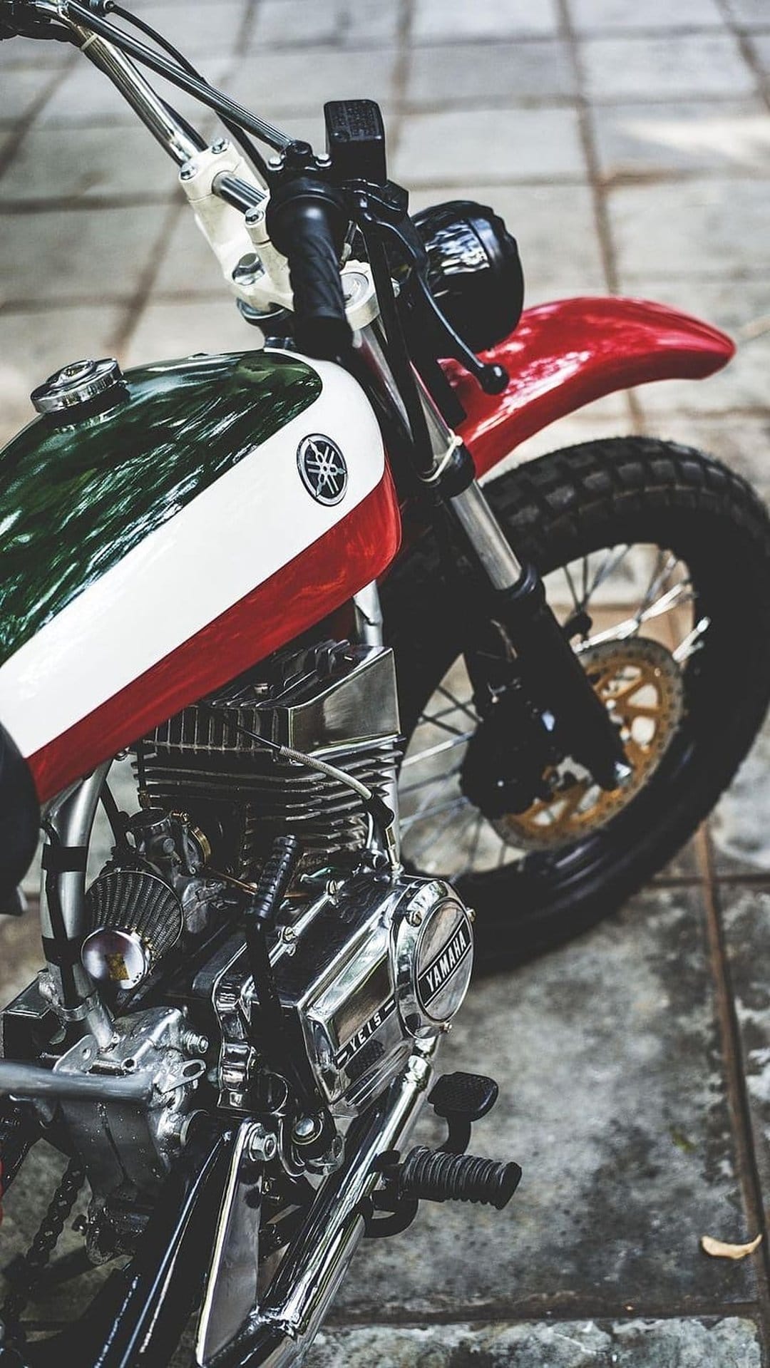 Vintage Yamaha motorcycle with a green and white fuel tank, chrome engine parts, and black knobby tires.