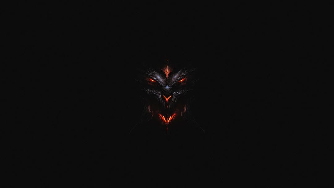Demonic face with glowing red eyes and a fiery mouth emerging from deep shadows on a black background.