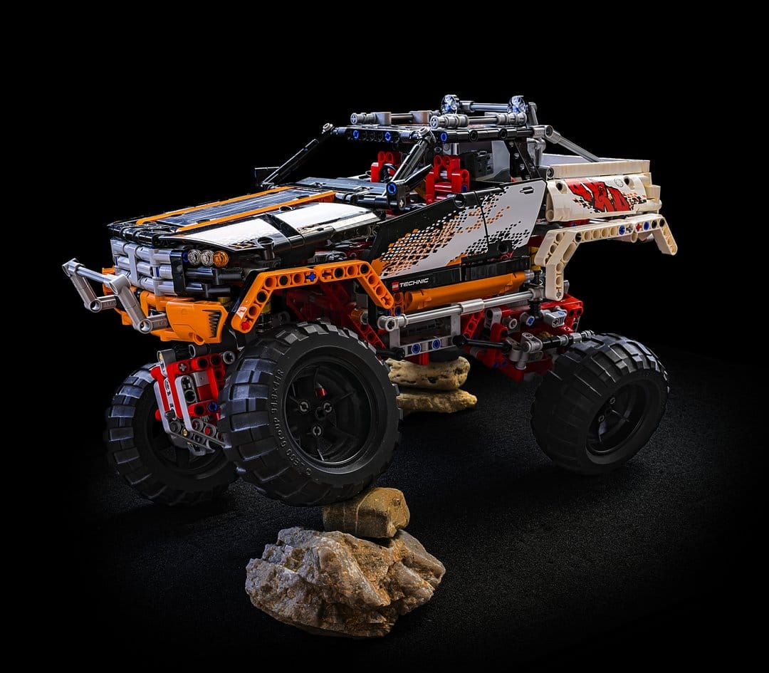 LEGO Technic off-road truck with orange panels, large black tires, and detailed mechanical suspension.