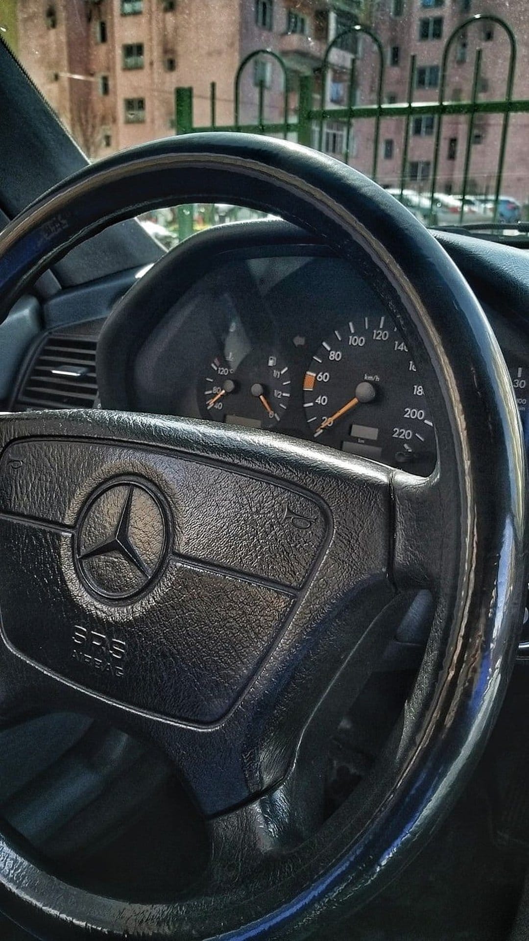 Mercedes-Benz W202 steering wheel with silver star emblem facing an analog speedometer and tachometer gauge.