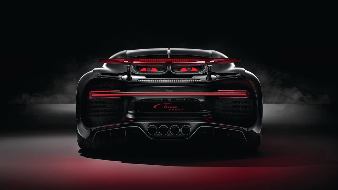 Rear view of a black Bugatti Chiron Sport hypercar with a glowing red LED light bar and quad exhaust in smoke.