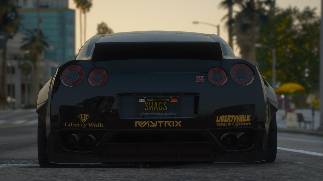 Rear view of a black Nissan GT-R with a widebody kit and gold decals under a sunset sky.