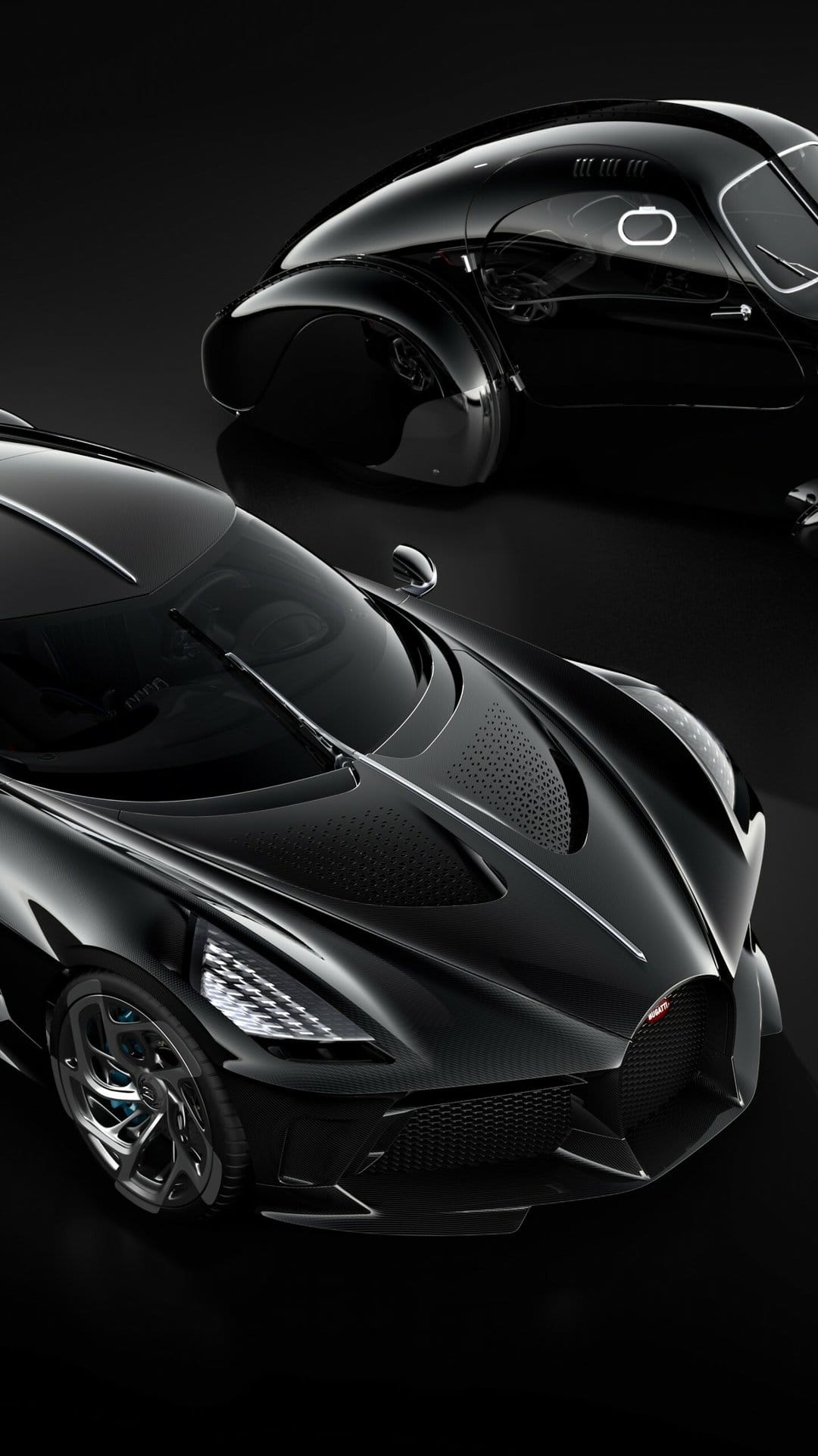 Two black Bugatti cars, a modern carbon fiber hypercar and a vintage coupe, against a dark studio background.