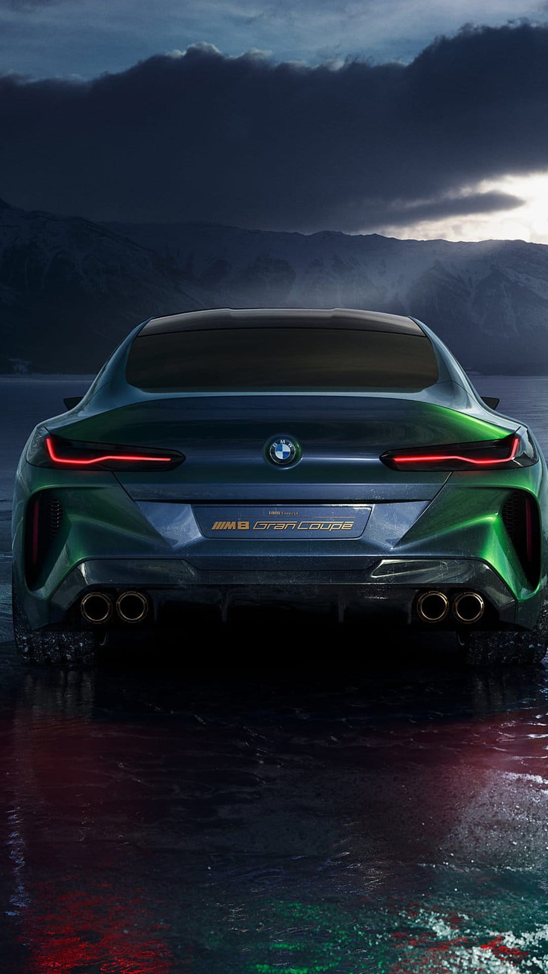BMW M8 Gran Coupe rear view with lit red taillights on a wet reflective surface under dark atmospheric lighting.