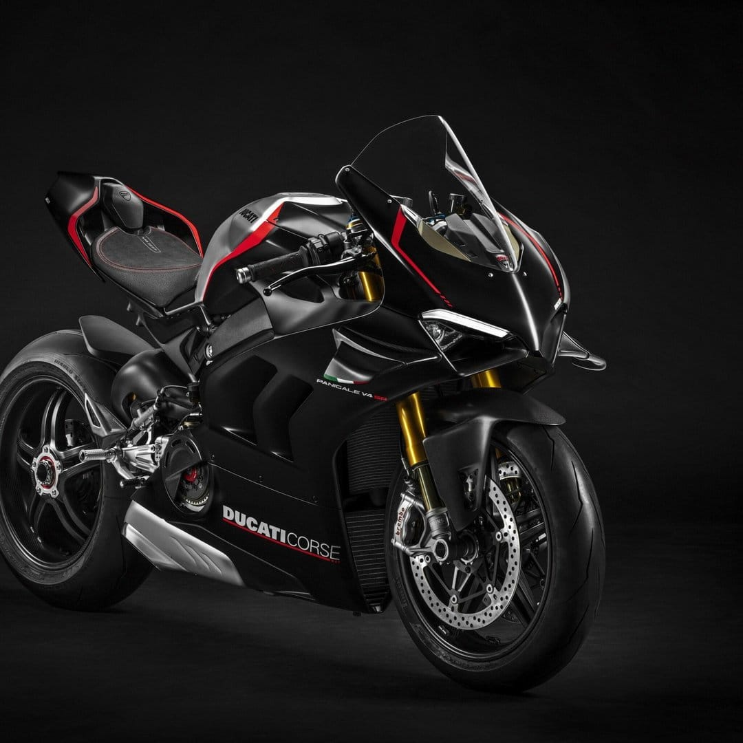 Matte black Ducati Panigale V4 SP motorcycle with red accents and gold forks against a dark studio background.