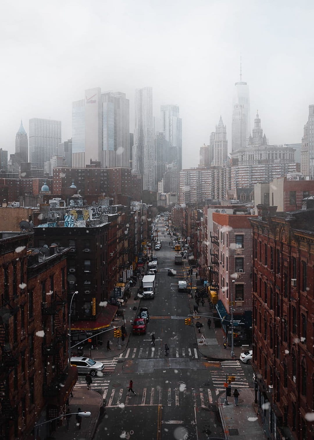 Misty Manhattan street view from above featuring historic brick buildings and foggy skyscraper silhouettes.