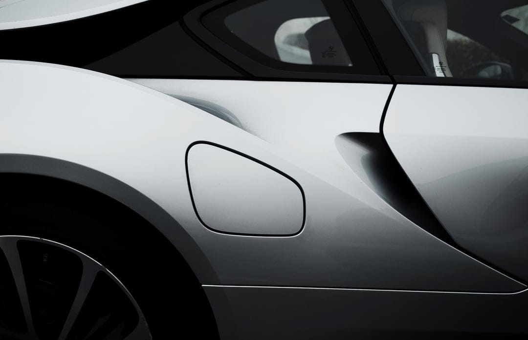 Silver sports car fuel door and aerodynamic rear panel with reflective metallic paint and sharp body lines.