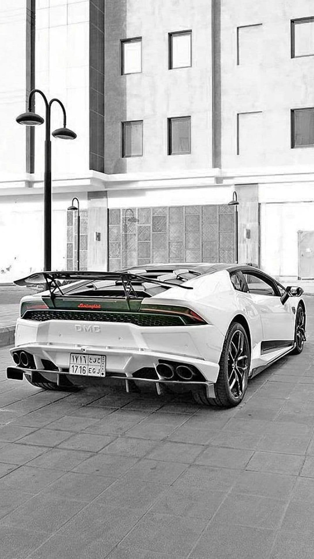 White Lamborghini Huracán Performante with a large rear wing parked on a stone street by a modern building.