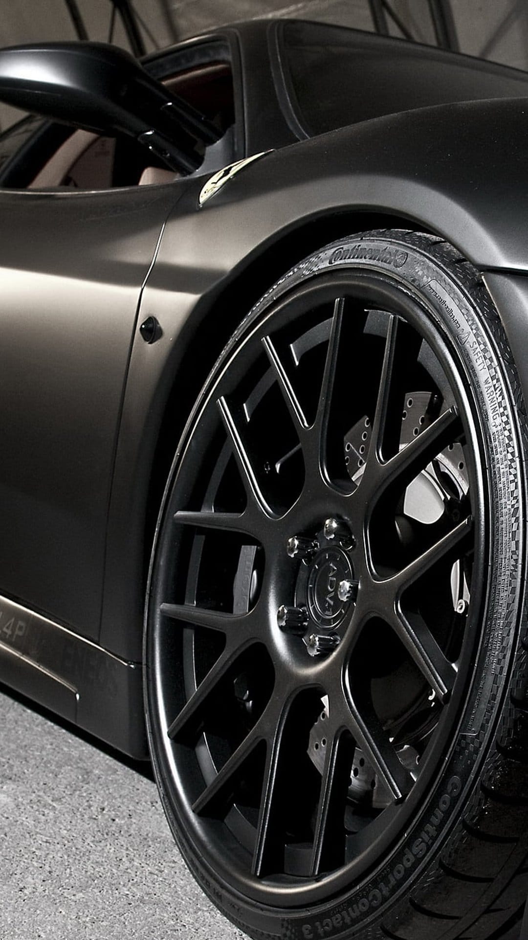 Matte black Ferrari 458 Italia front wheel features multi-spoke rims and cross-drilled performance brake rotors.