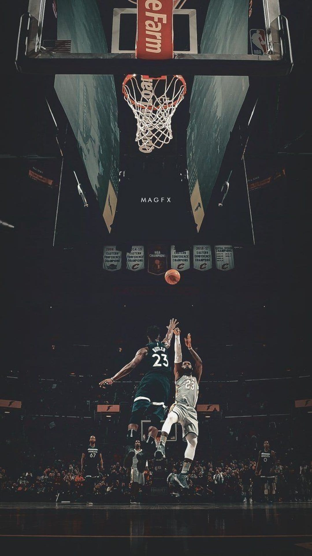 Two basketball players leap toward a rim and backboard in a dark arena with glowing overhead stadium lights.