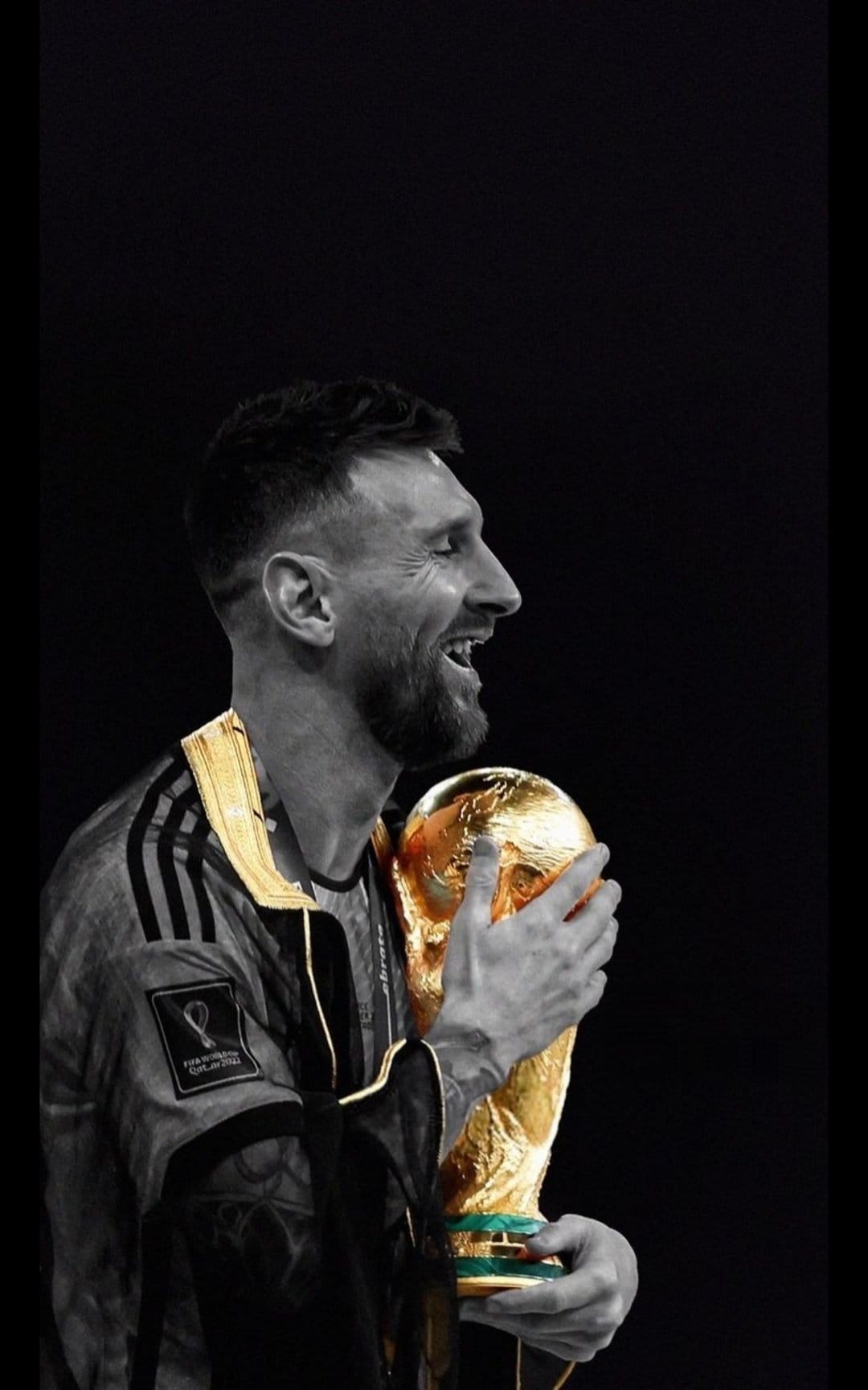Lionel Messi closes his eyes while holding the World Cup trophy against a dark, high-contrast background.