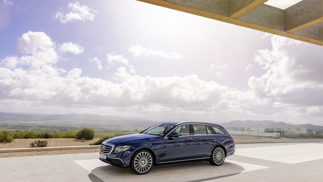 Navy blue Mercedes-Benz E-Class Estate on a stone terrace with a scenic valley and mountain background.