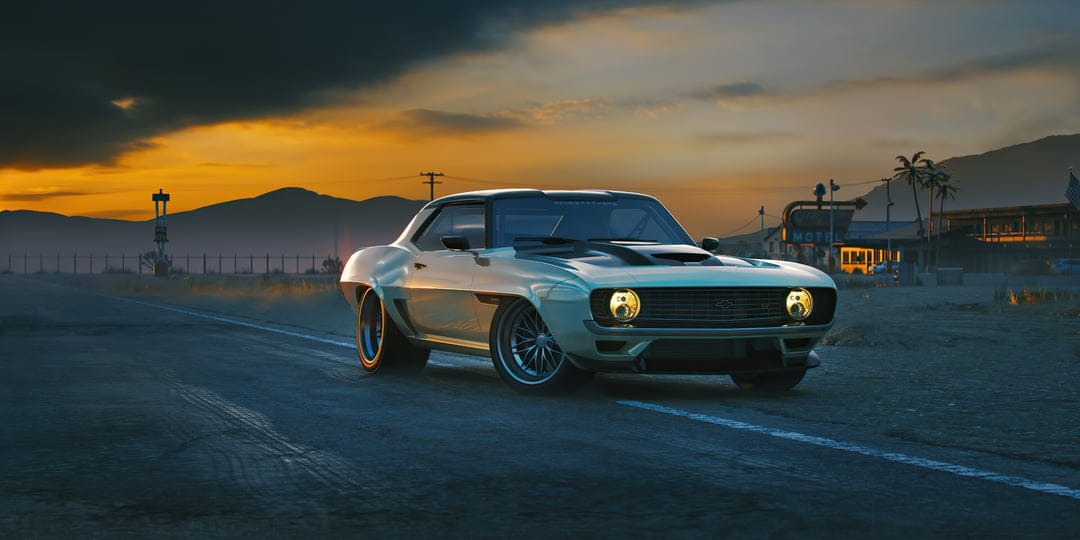 White custom 1969 Chevrolet Camaro with yellow headlights on a desert road against a dramatic sunset sky.