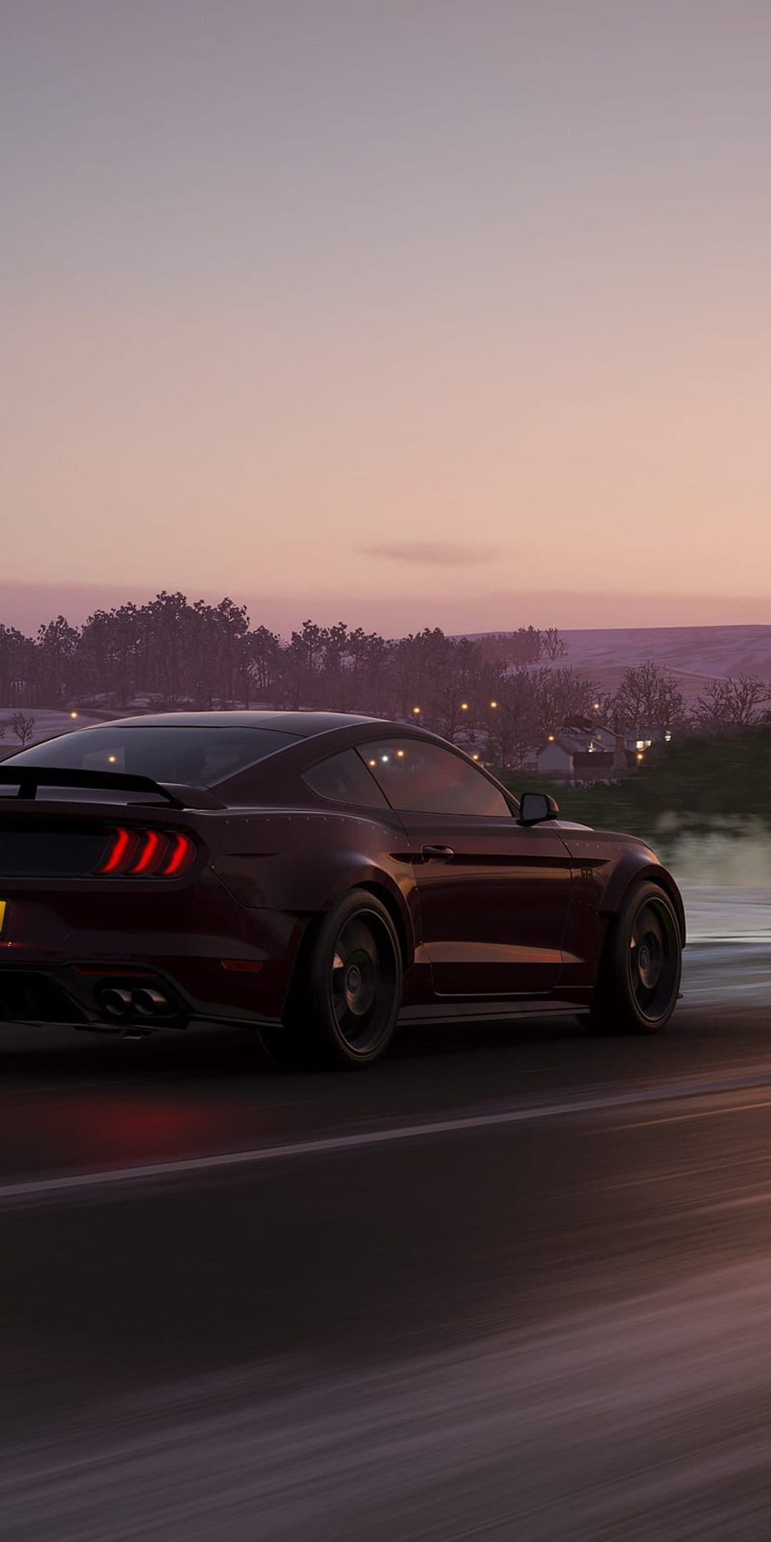 Scarlet Mustang muscle car driving down a road at dusk with illuminated taillights and a purple twilight sky.