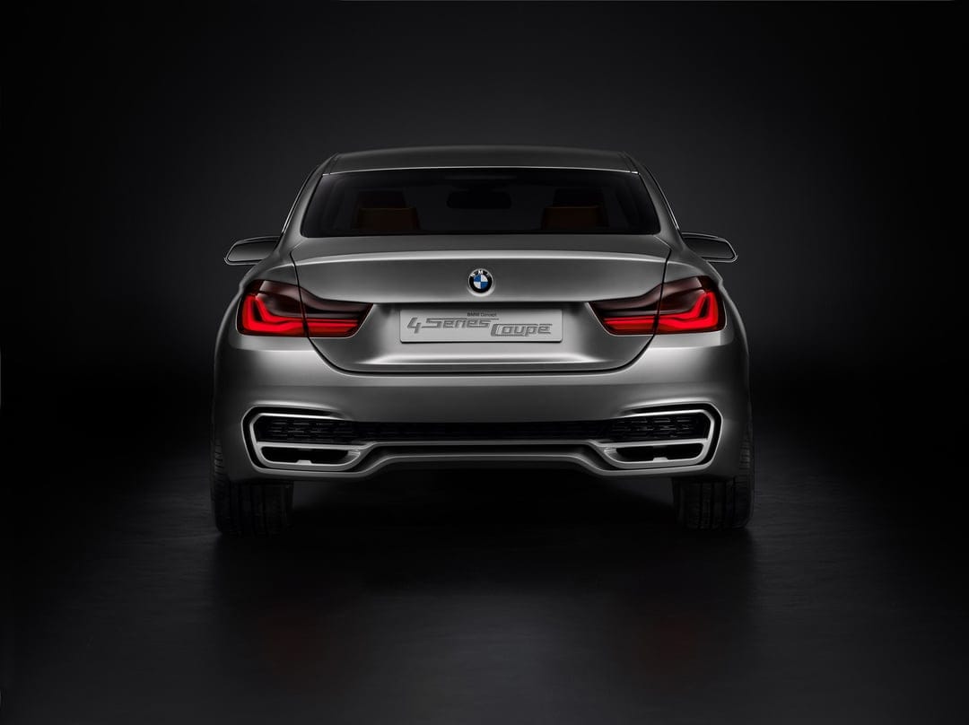 Rear of a silver BMW Concept 4 Series Coupe with glowing red L-shaped taillights on a dark black background.