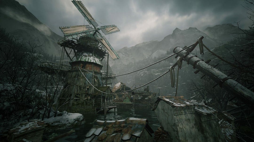 Weathered wooden windmill over a dark lake in a snowy, mountainous village under a cloudy, overcast sky.