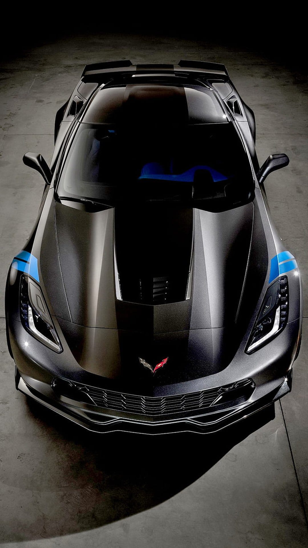 Matte black Corvette Z06 with blue stripes viewed from above, highlighting the front grille and hood emblem.