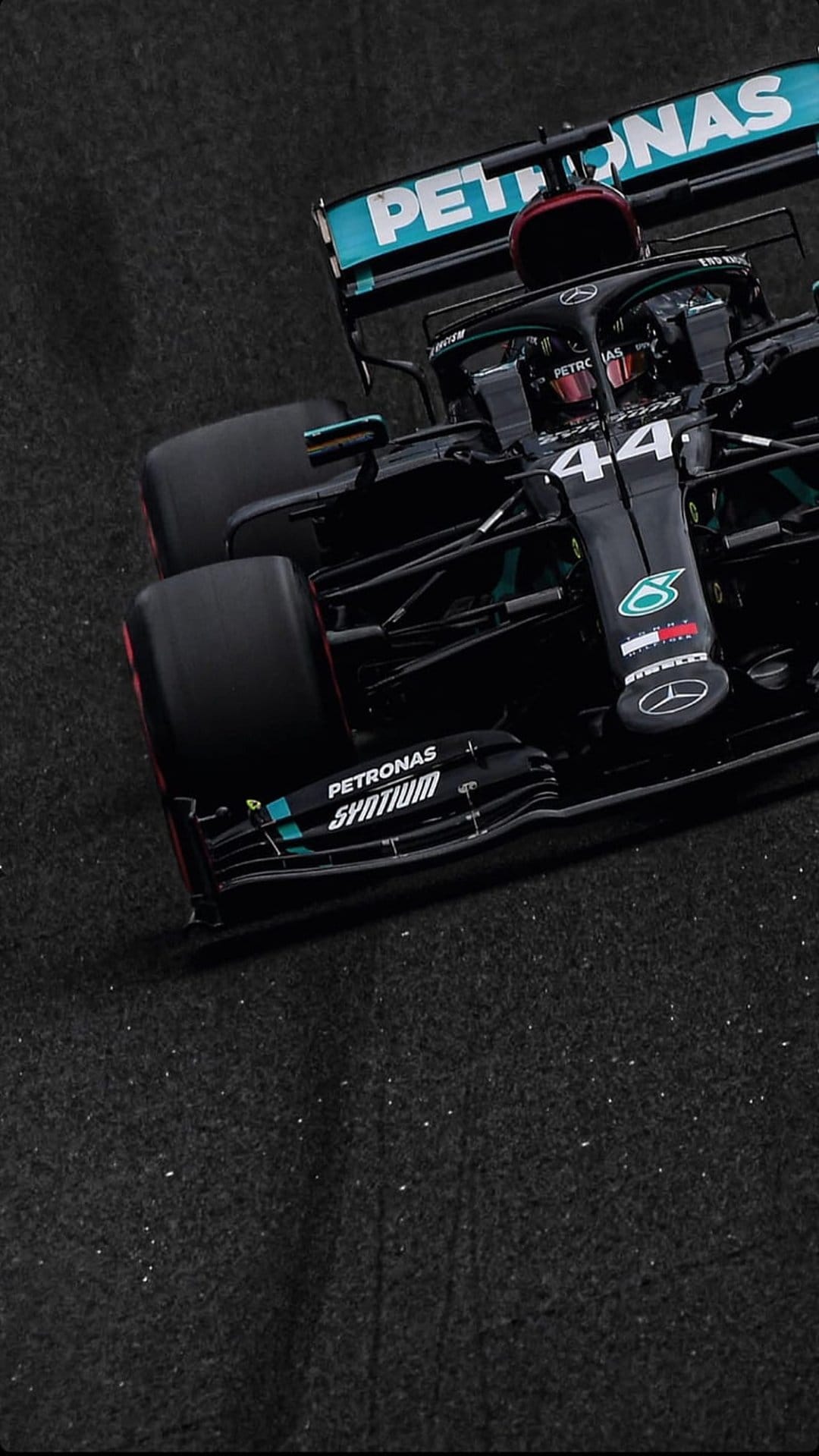 Lewis Hamilton's black and turquoise Mercedes F1 car maneuvers on a racing circuit at high speed from a low angle.