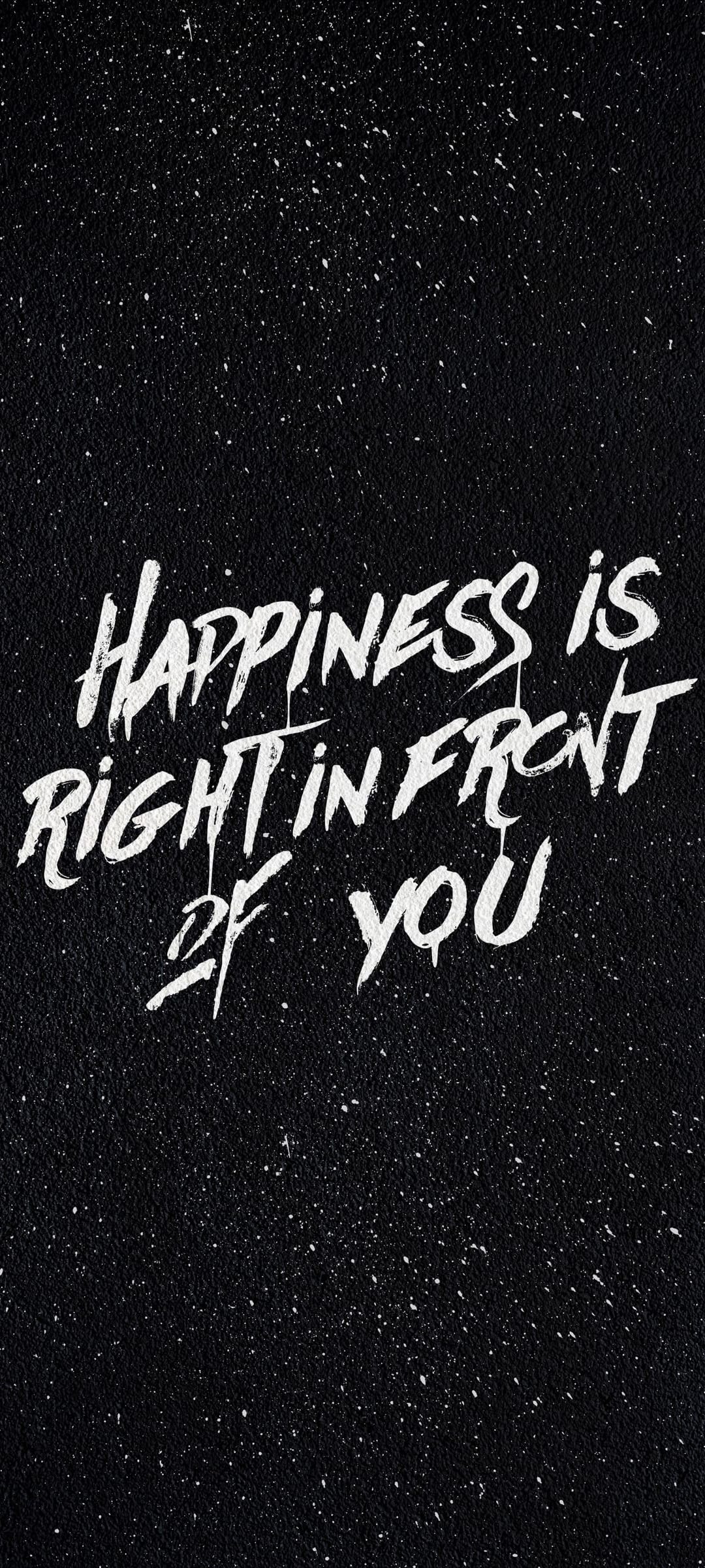 White hand-drawn quote text saying happiness is right in front of you on a black starry textured background.
