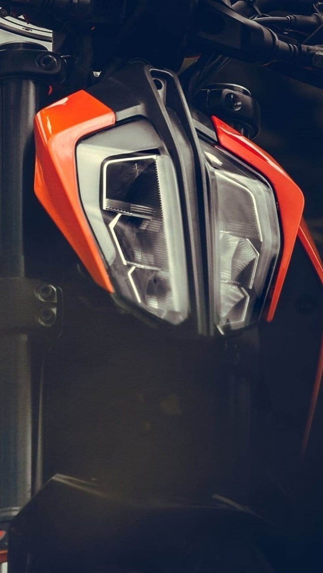 KTM motorcycle LED headlight assembly with sharp angular orange fairings and reflective metallic details.
