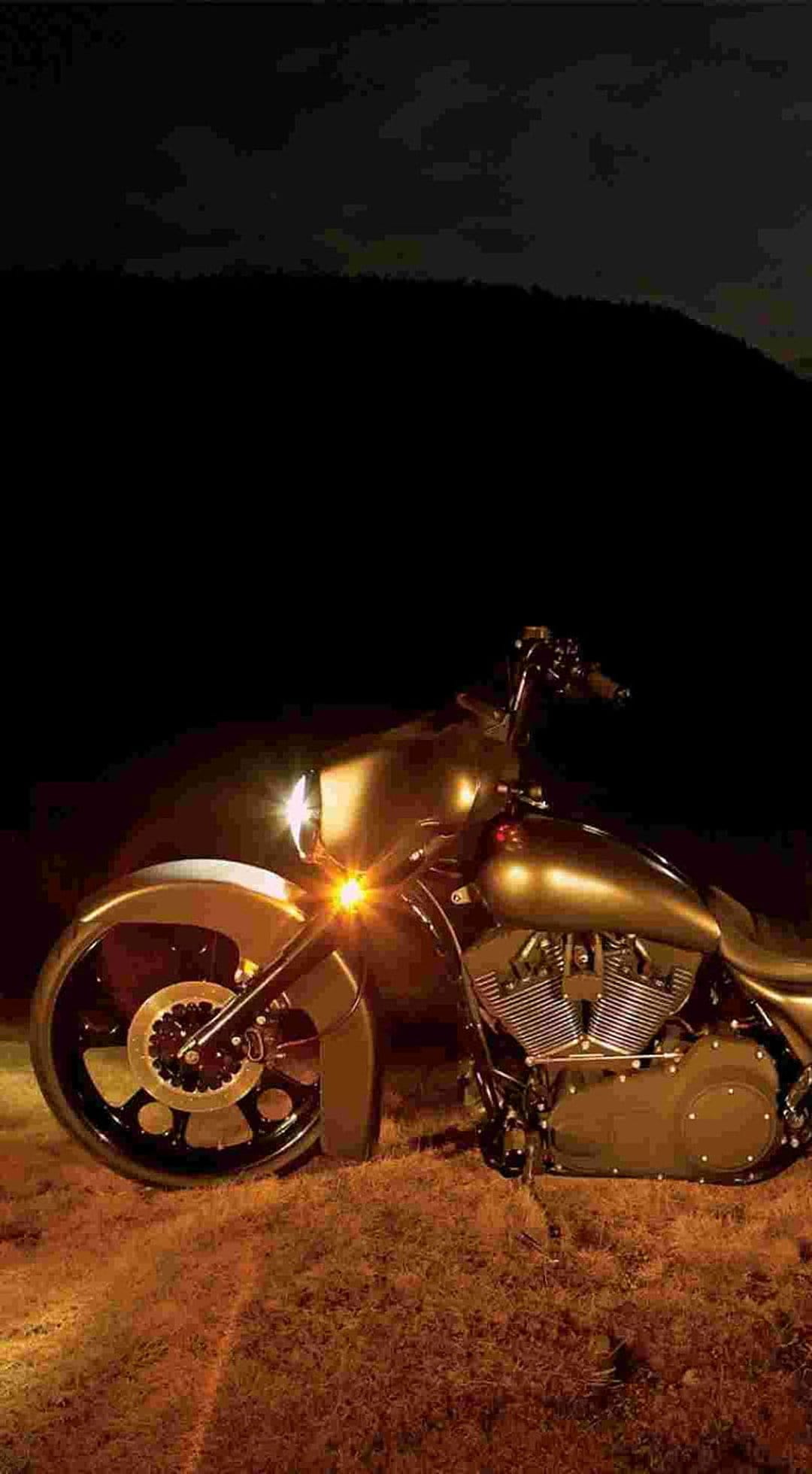 Golden custom chopper motorcycle with a glowing headlight and chrome engine reflecting warm light at night.
