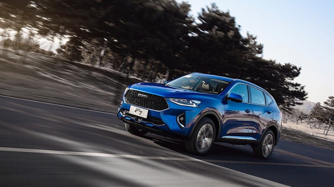 Blue SUV driving fast on a paved road with heavy motion blur and dark trees in the background.