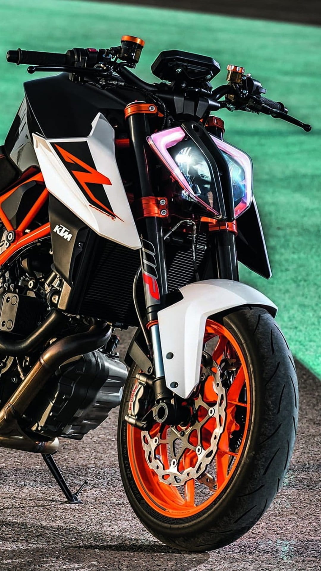 KTM motorcycle front wheel with an orange rim, LED headlight with pink glow, and silver suspension forks.