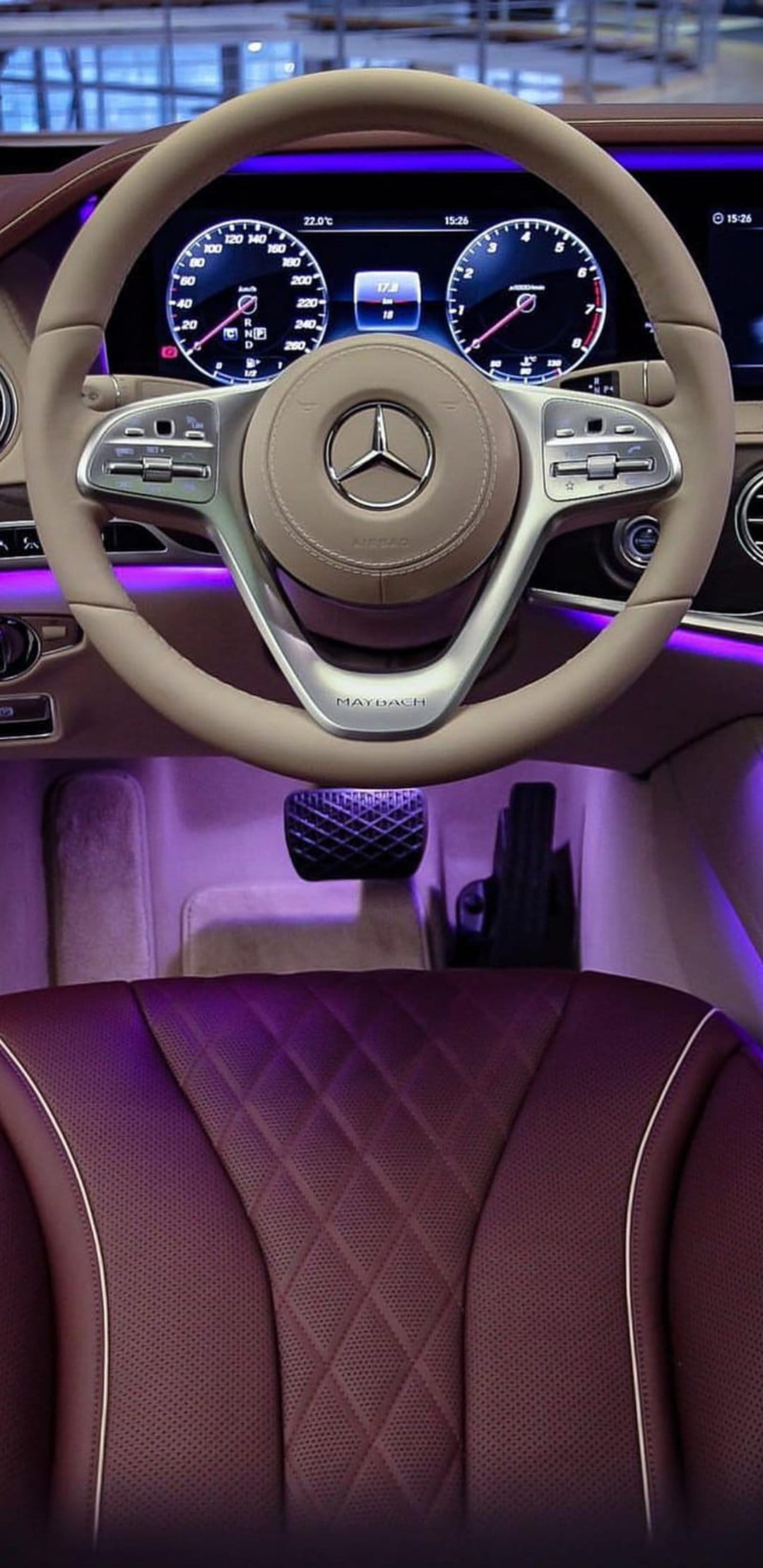 Mercedes-Maybach steering wheel and burgundy diamond-quilted leather seats glowing under purple ambient light.