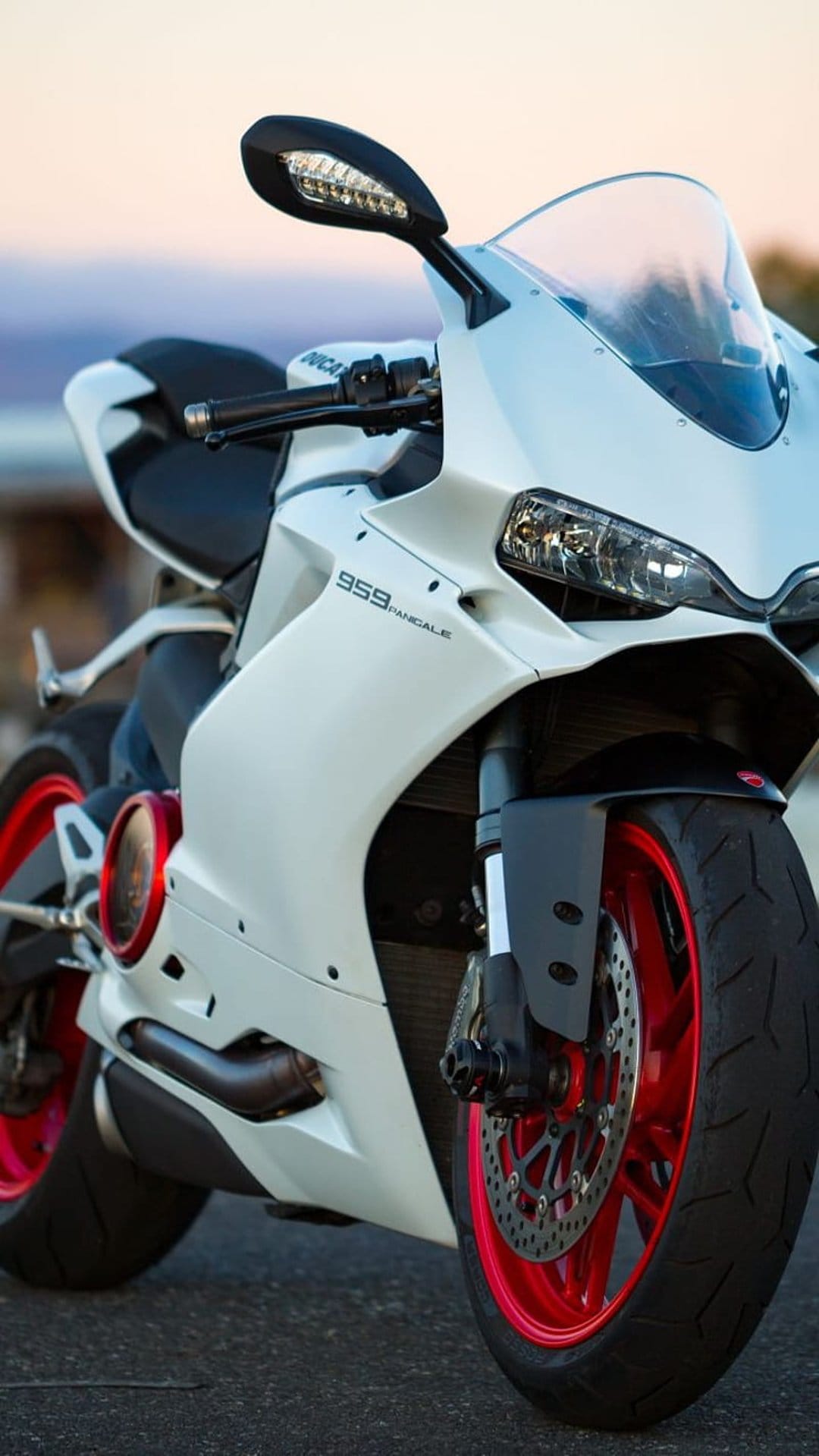 Ducati 959 Panigale motorcycle featuring white fairings and bright red wheels in a detailed close-up shot.