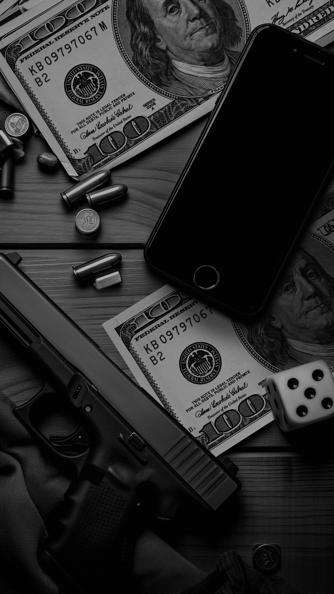 Handgun, stacks of hundred-dollar bills, a smartphone, and dice lie on a dark surface in a moody flat lay.