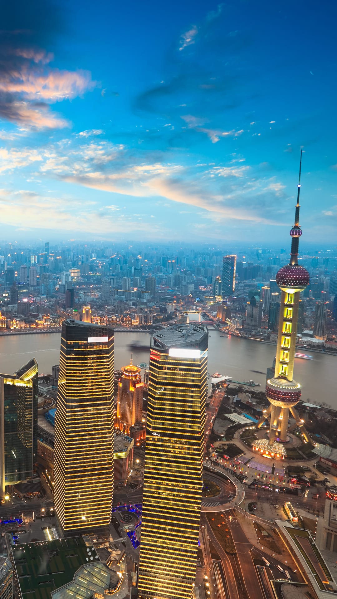 The Oriental Pearl Tower and skyscrapers illuminate the Shanghai skyline along the Huangpu River at twilight.
