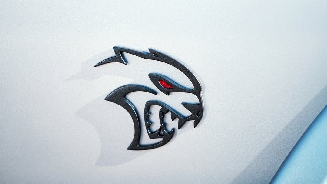 Gunmetal Dodge Hellcat Redeye car emblem with a textured red eye on a metallic silver vehicle surface.