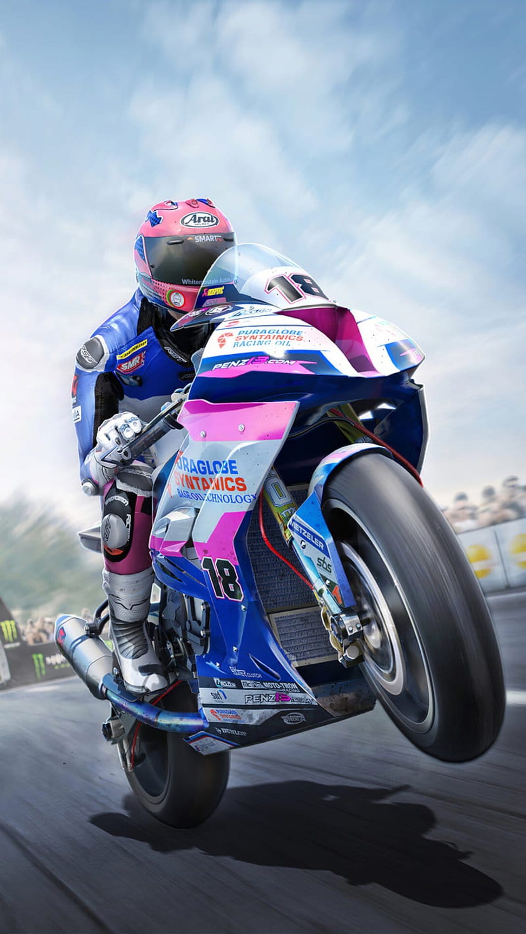 Motorcyclist in a pink helmet performs a wheelie on a blue and pink sportbike along a sunny asphalt race track.