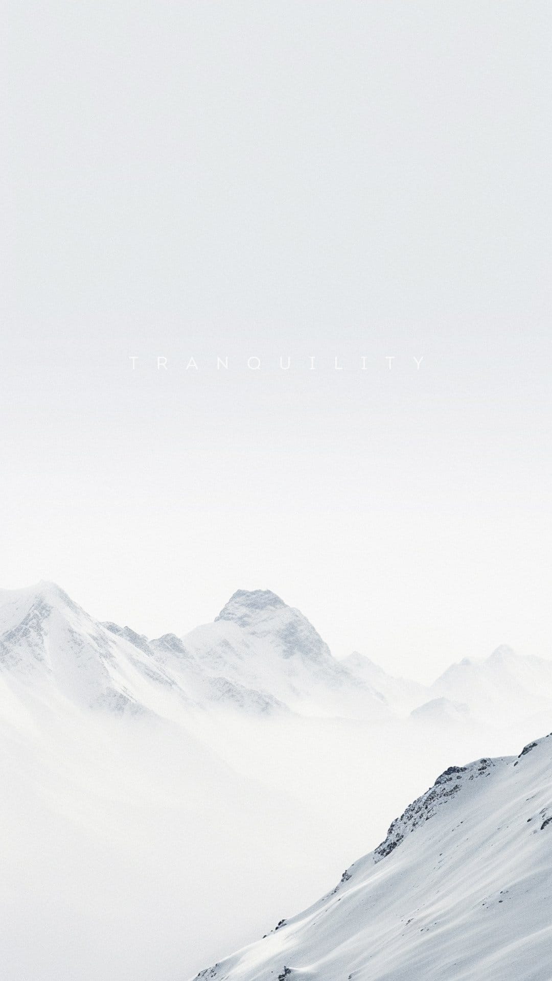 Snow-capped mountain peaks emerge through thick white mist with the word Tranquility centered in the upper frame.