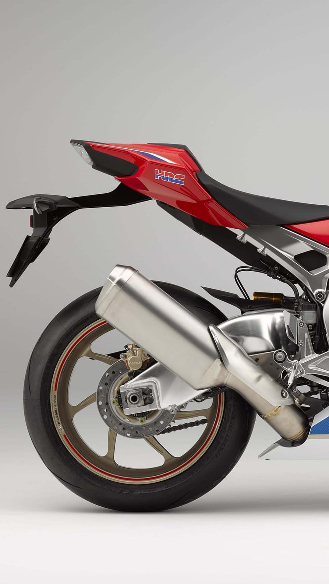 Rear wheel of a red Honda CBR motorcycle showcasing a metallic exhaust pipe and braking system details.