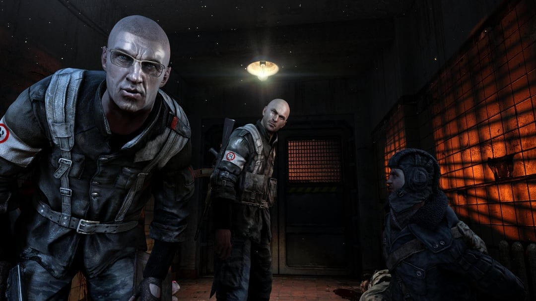 Bald man with glasses and soldiers in a dark industrial room with orange light through barred windows.