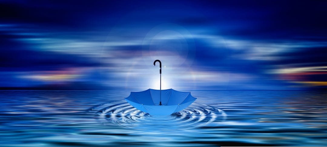Blue umbrella floating on still water with gentle ripples under a blurred twilight sky with sunset hints.