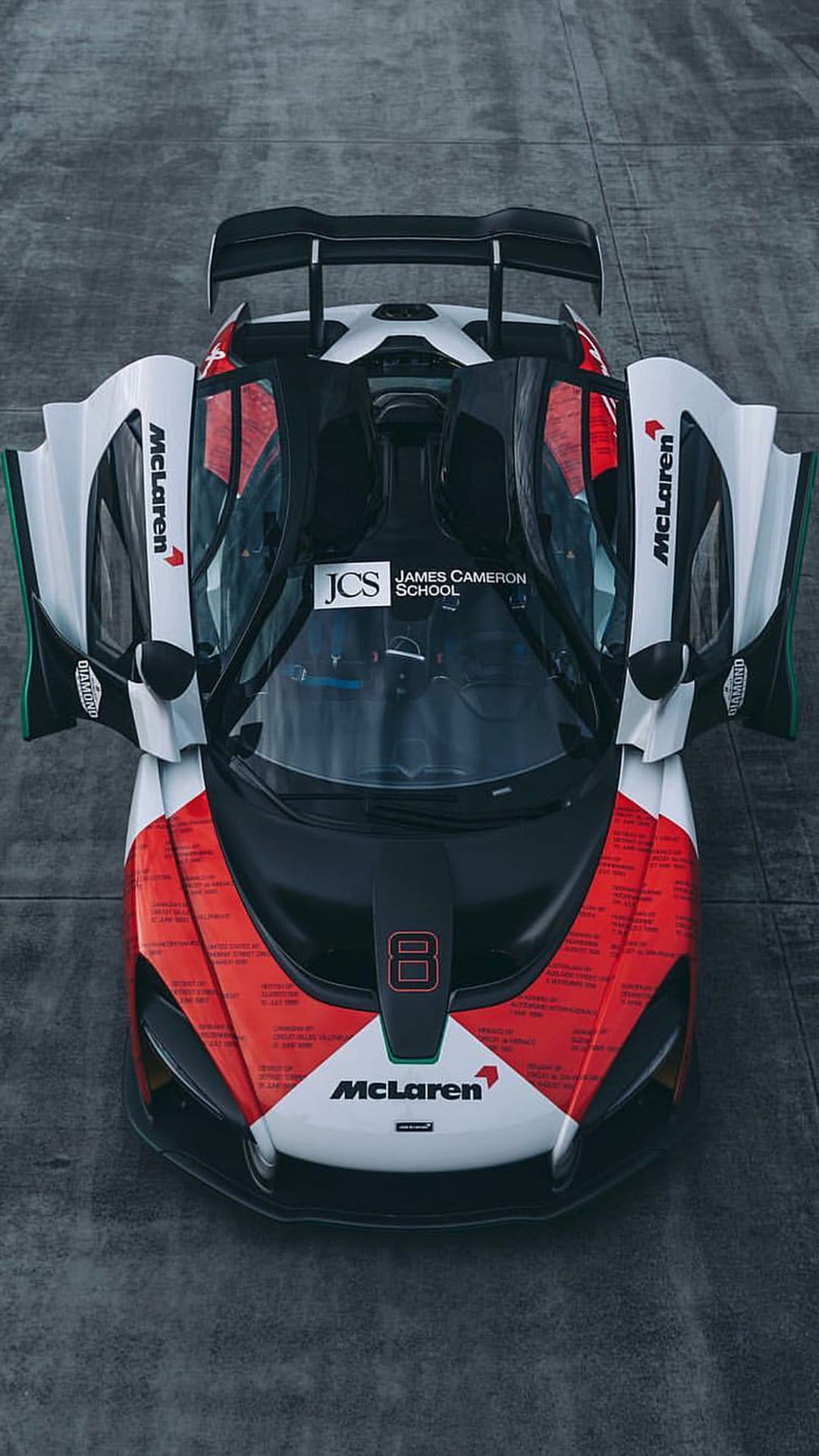 McLaren Senna GTR race car with open dihedral doors and red livery seen from a top-down aerial perspective.