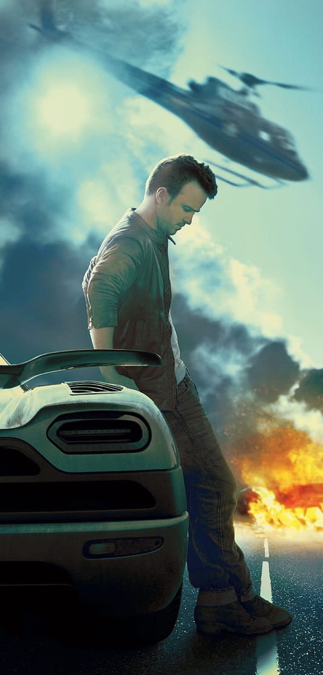 Man in dark clothing leans on a teal sports car with a helicopter flying over an orange fire on a highway.