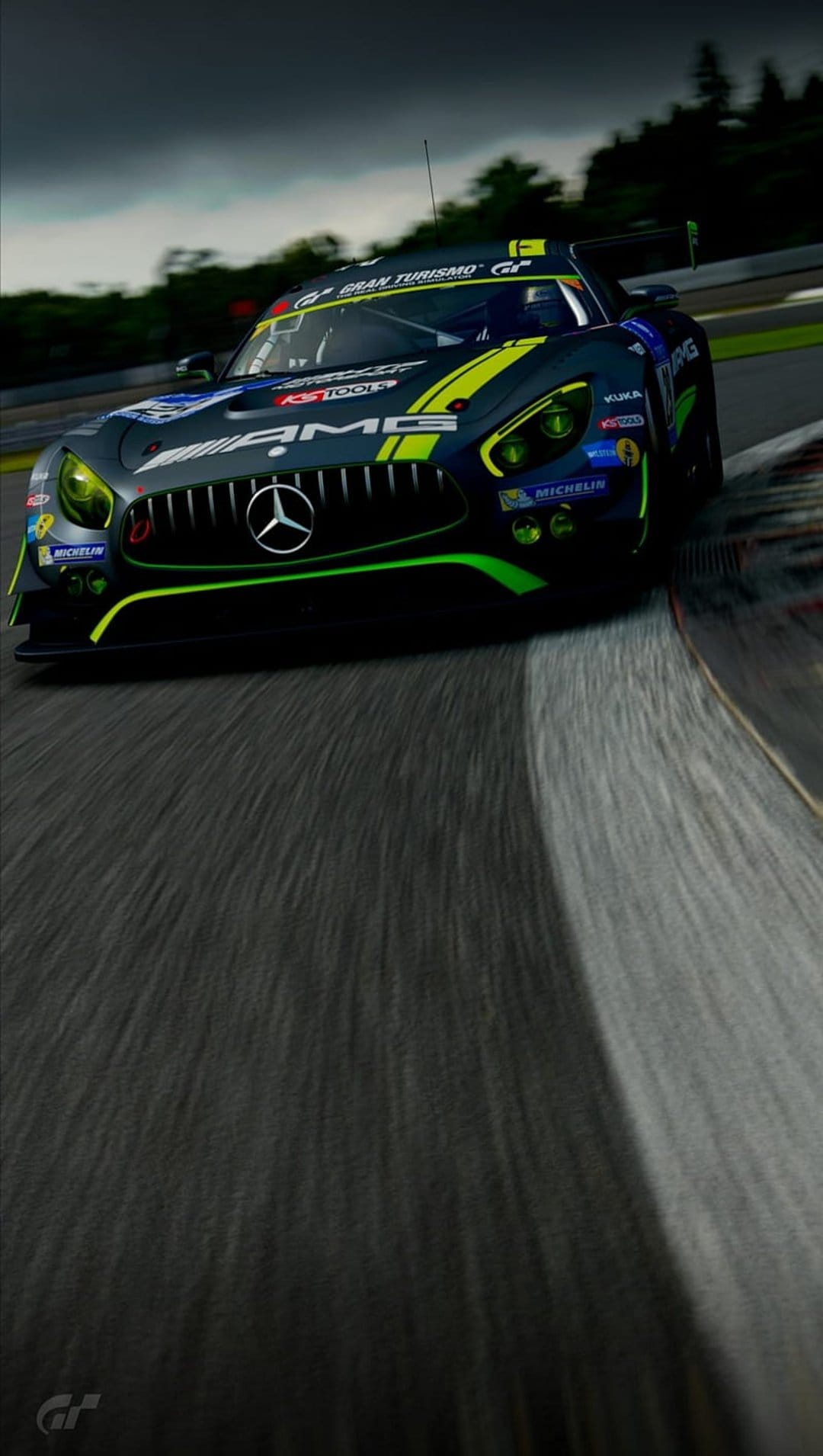 Mercedes-AMG GT3 race car with lime green trim and yellow lights speeds on a track under a dramatic cloudy sky.